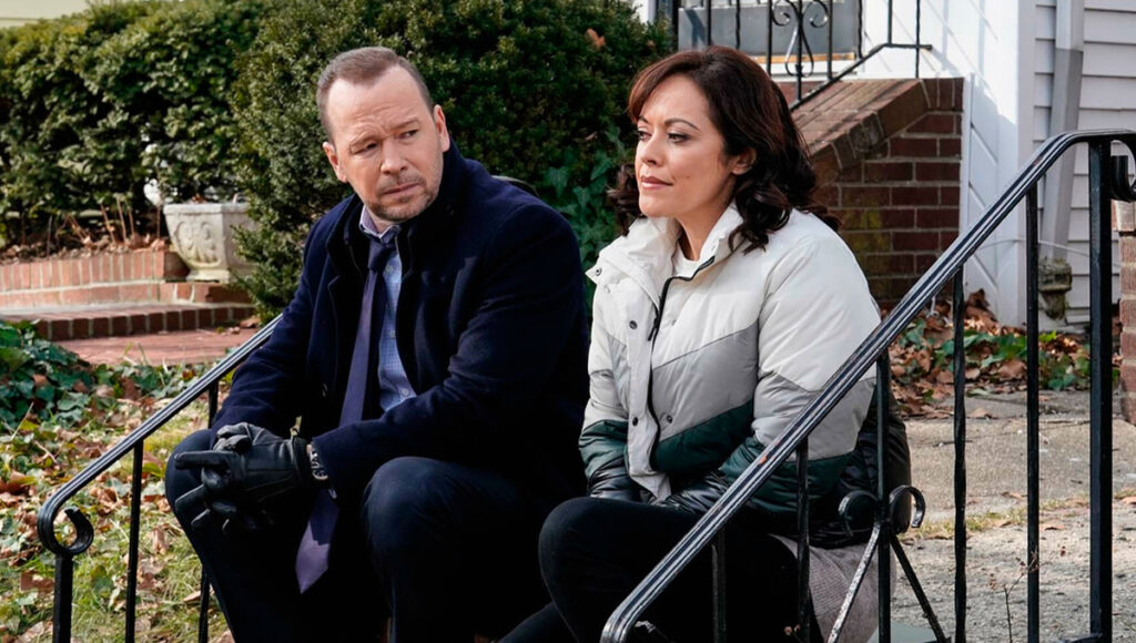 Os personagens Danny Reagan e Maria Baez sentados na escada em Blue Bloods