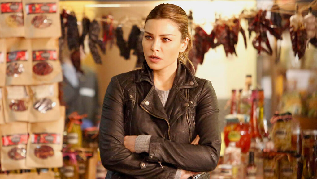 A atriz Lauren German como a detetive Chloe Decker de braços cruzados em uma loja
